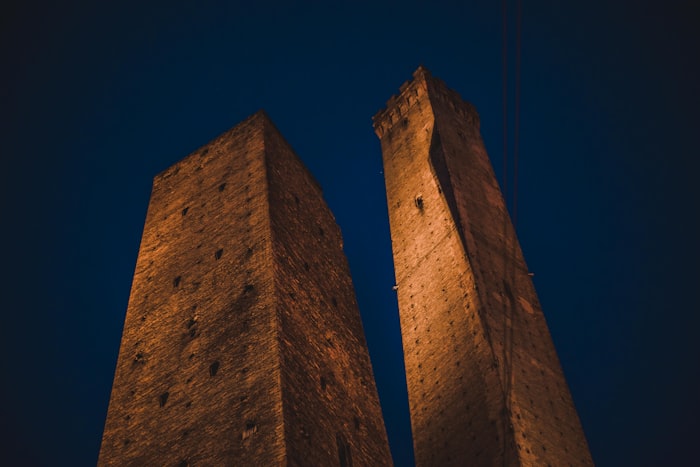 As Duas Torres de Bolonha iluminadas contra o céu noturno