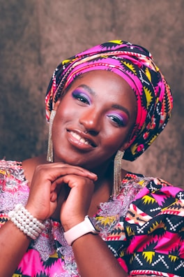 A cheerful customer trying on a colorful headwrap in front of the store mirror.
