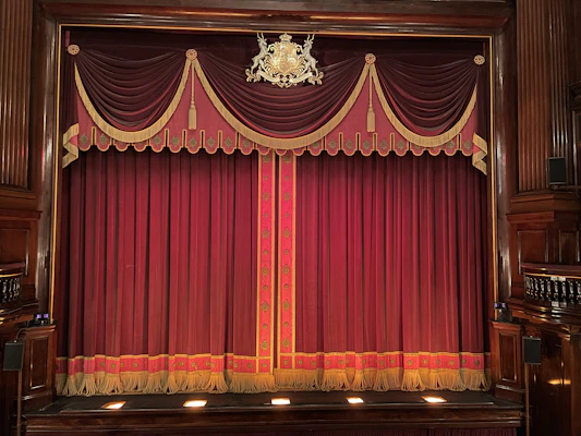Vintage miniature theater stage with rich velvet curtains and golden accents.