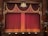 An ornate theater stage with rich burgundy curtains adorned with gold tassels and decorative patterns. The emblem above the curtains adds a touch of elegance to the classical setting. Wooden panels frame the sides, enhancing the traditional atmosphere.