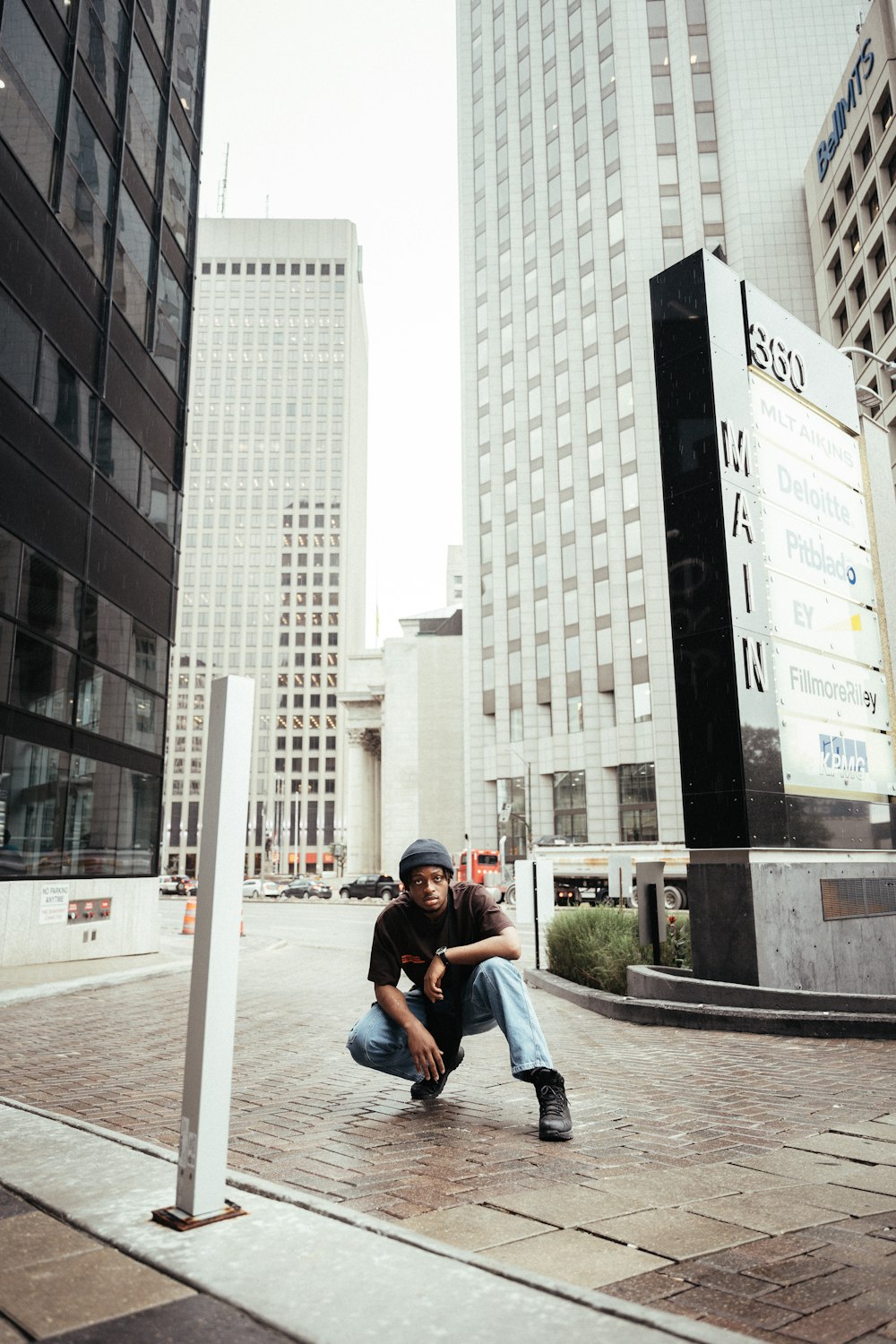 a man sitting on a sidewalk in front of tall buildings