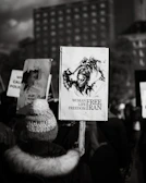 A close-up of a young Iranian woman holding a candle during a peaceful protest at dusk.