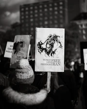 A close-up of a young Iranian woman holding a candle in a peaceful vigil.