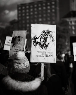 A close-up of a young Iranian woman holding a candle during a peaceful protest at dusk.