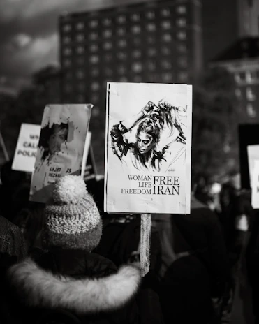 A close-up of a young Iranian woman holding a candle in a peaceful vigil.