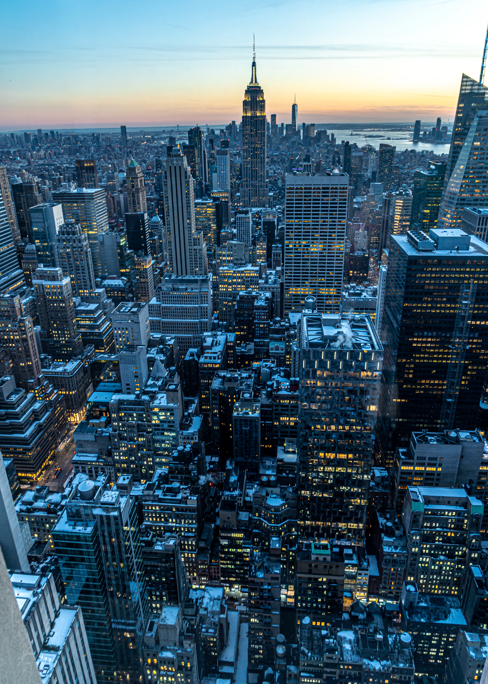 The iconic New York City skyline at dusk, with warm earthy tones reflecting off the glass windows and a hint of the bustling city below.