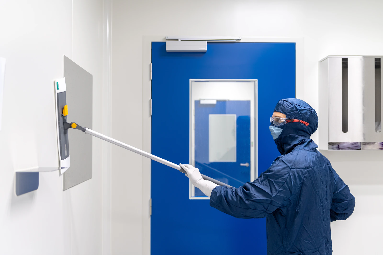 Techniker im Schutzanzug, der eine Oberfläche desinfiziert