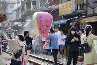 A joyful group of travelers exploring a vibrant street market in Thailand under colorful lanterns.
