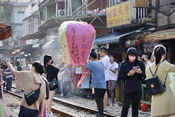 A joyful group of travelers exploring a vibrant street market in Thailand under colorful lanterns.