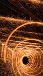 Concentric circles of golden light swirl into a central point, creating a dynamic tunnel effect against a dark background.