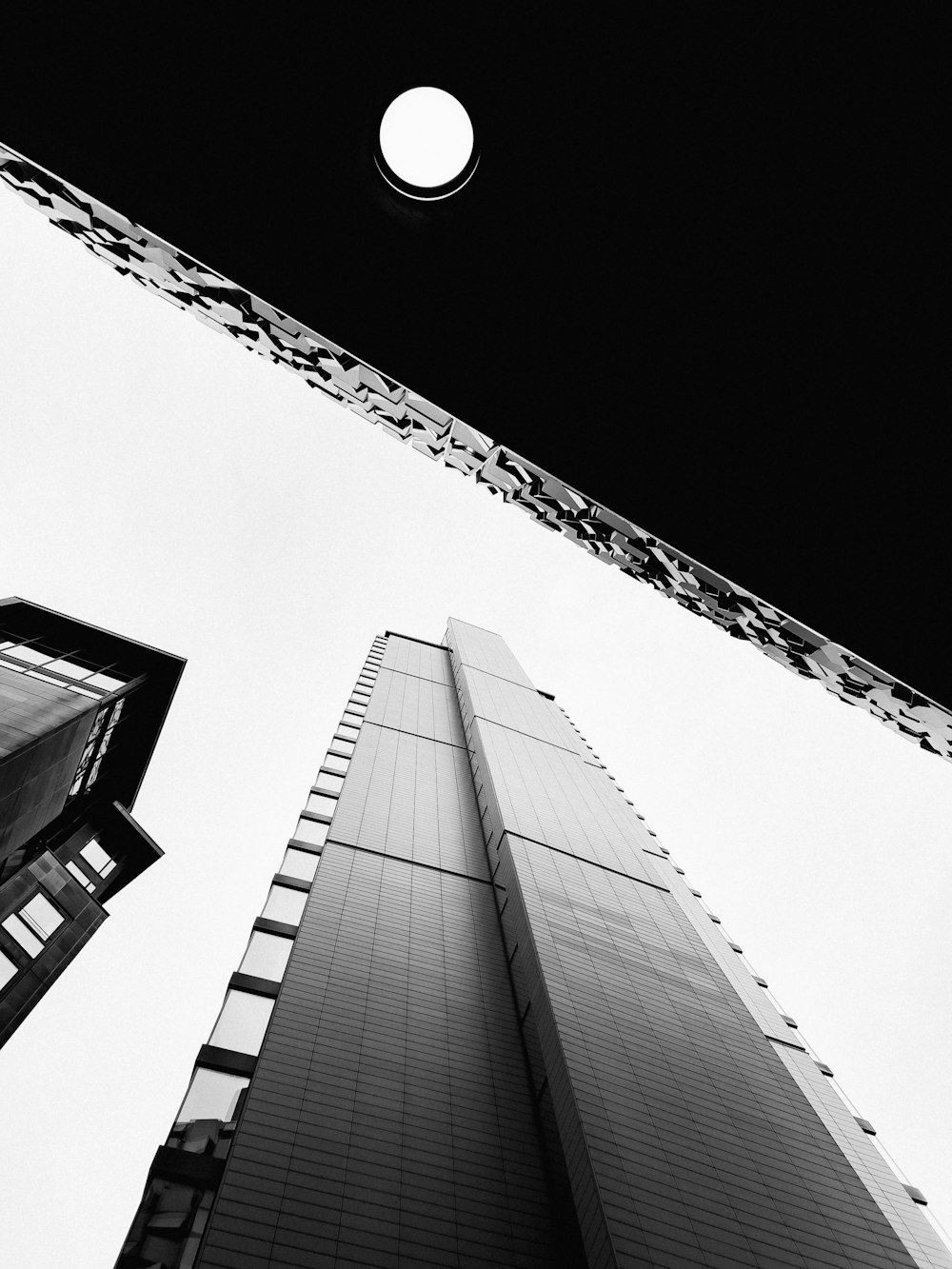 a moon in the sky above a couple of tall buildings