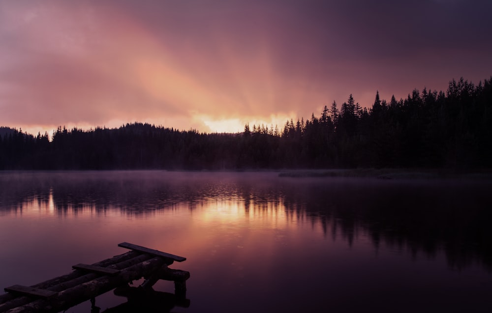 a lake with trees and a sunset