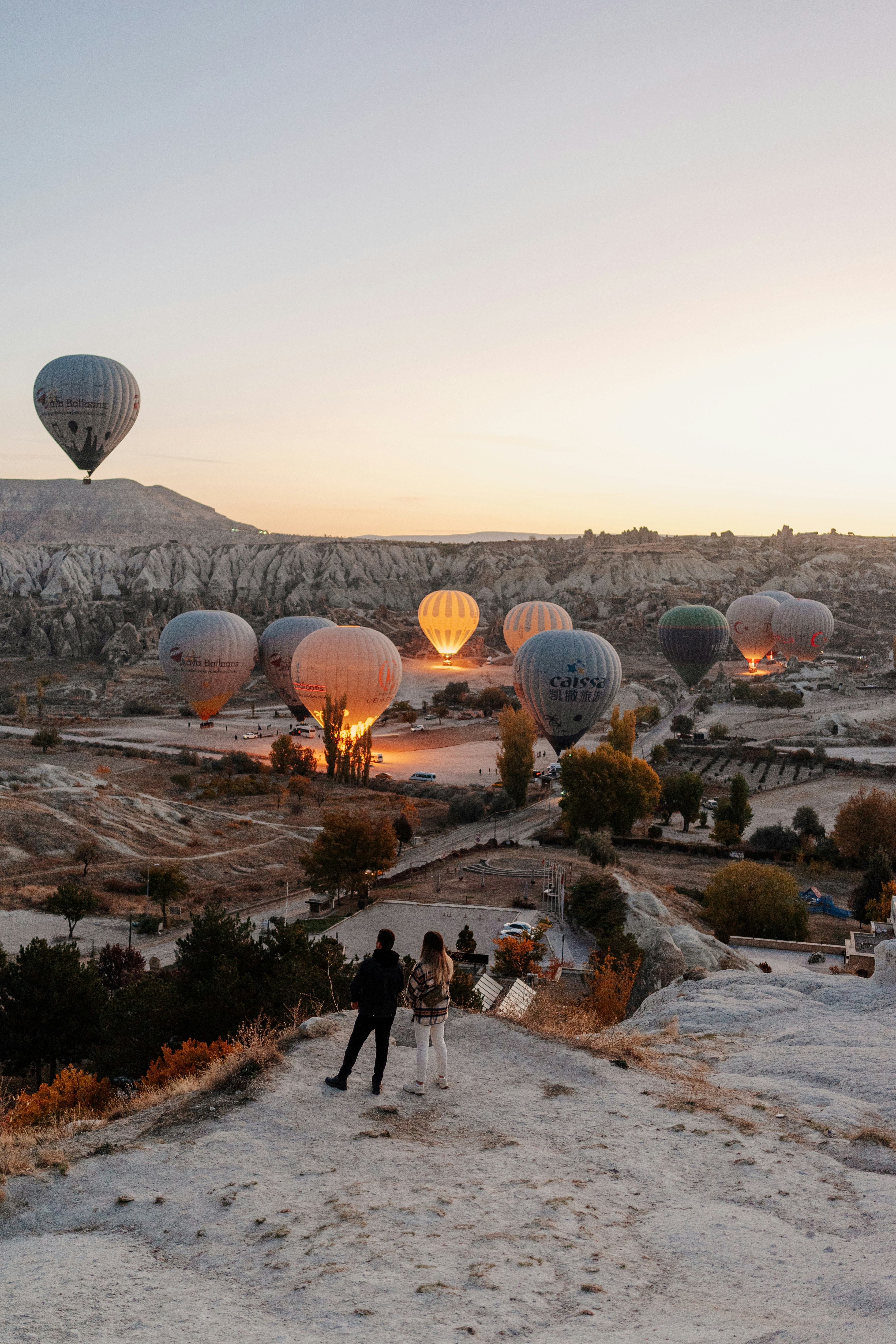 a group of people standing in front of a group of hot air balloons