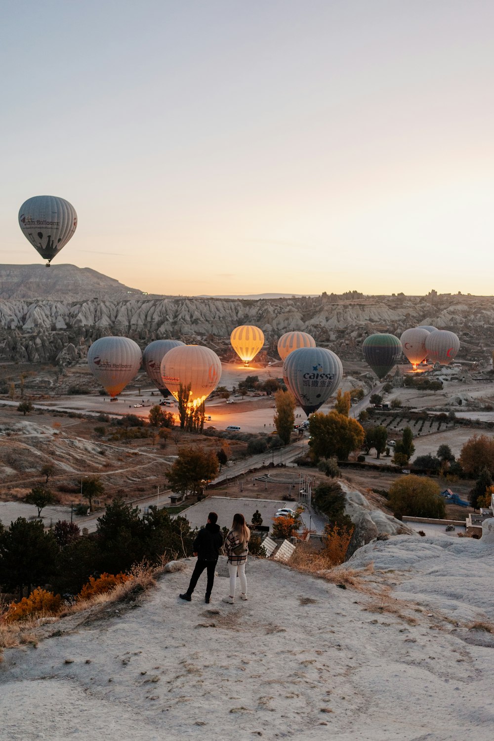 Un grupo de personas de pie frente a un grupo de globos aerostáticos