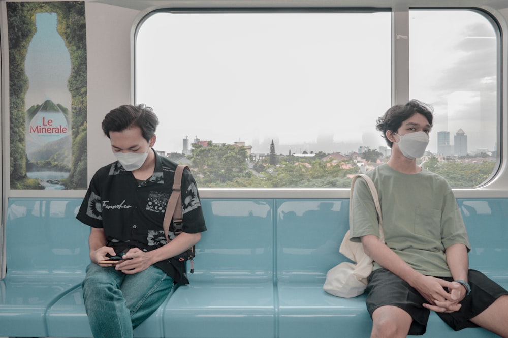 a couple of people wearing masks and sitting on a bus