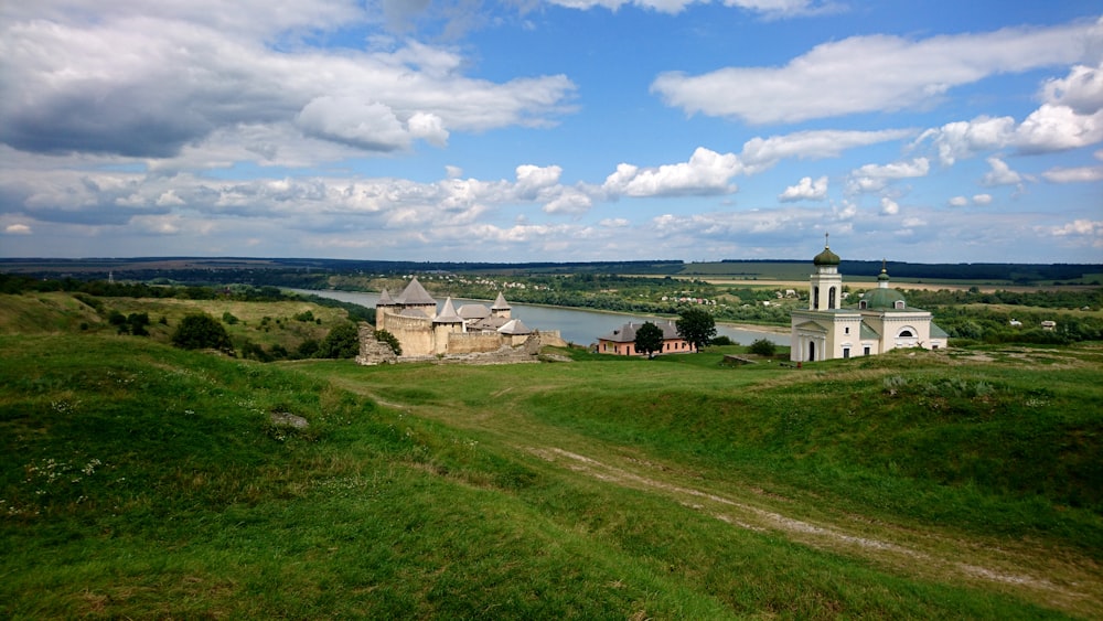 a grassy area with buildings and a body of water in the background