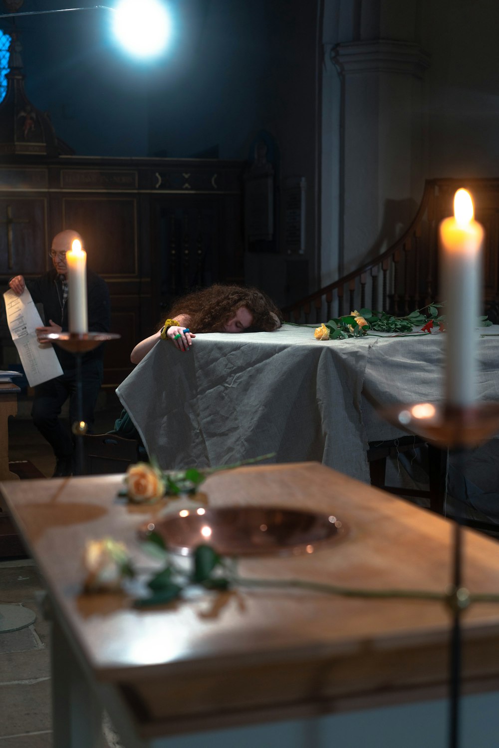 a person sleeping at a table with food and candles