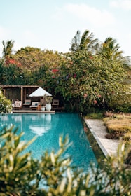An inviting hotel pool area surrounded by lush greenery.