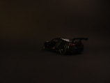 Side silhouette of the race car under dramatic lighting on a black background.