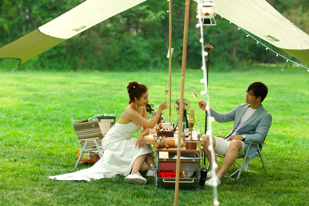 a man and woman sitting under a tent with food and drinks