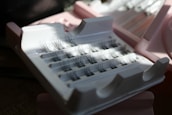 False eyelashes are neatly arranged in a plastic case with a few individual lashes missing. The case and surrounding area are lit by natural light creating some shadows.