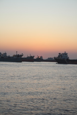 A panoramic view of a fleet of ships anchored near the Malaysian coastline at sunset.