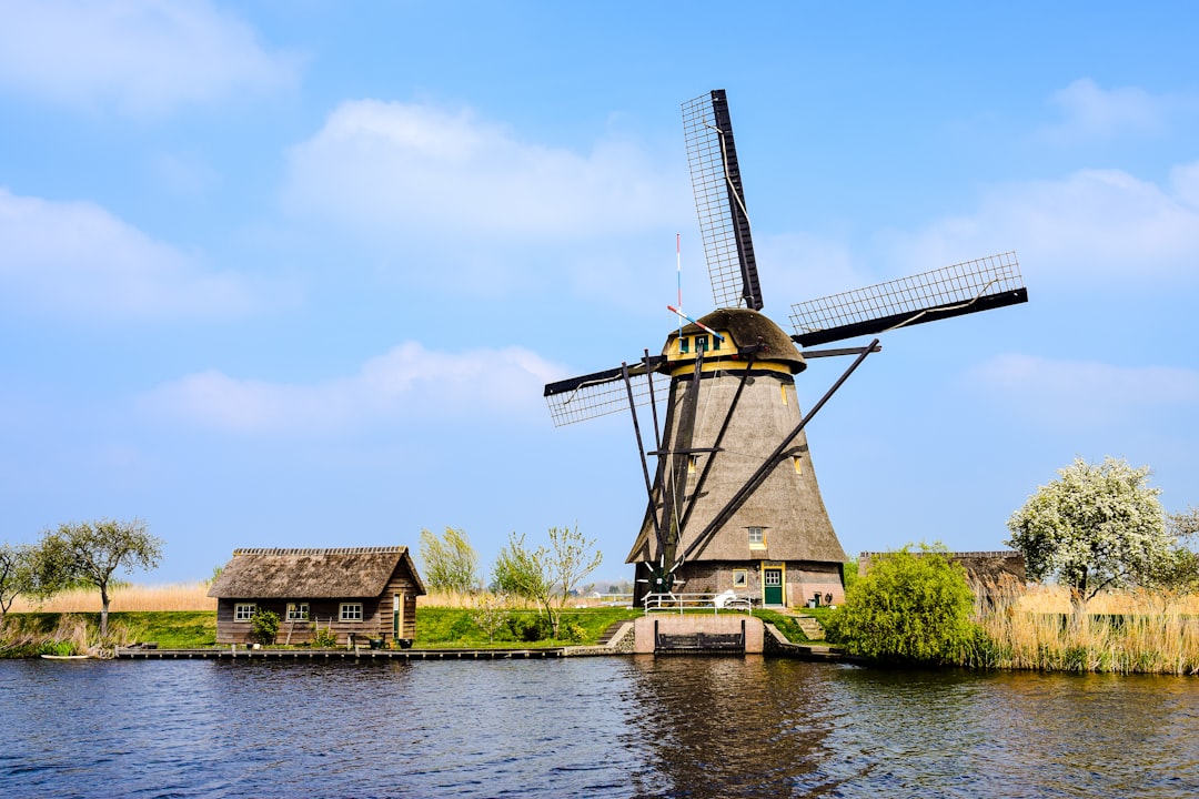 a windmill next to a body of water, Netherlands.