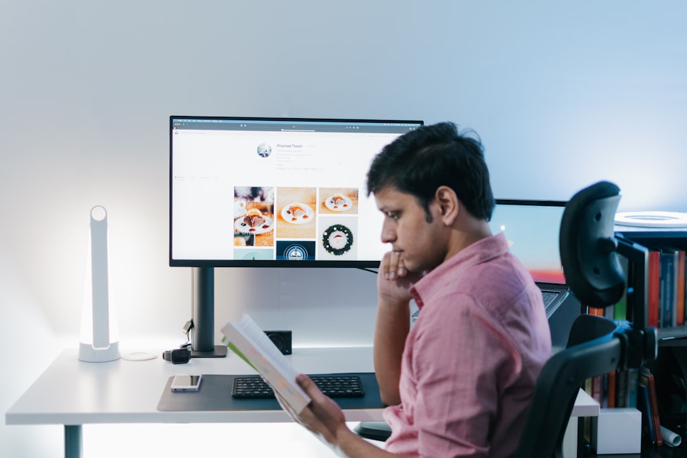 a person sitting at a desk with a computer and a monitor