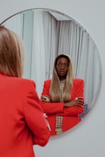 A stylish woman adjusting her custom-designed jacket in front of a mirror.