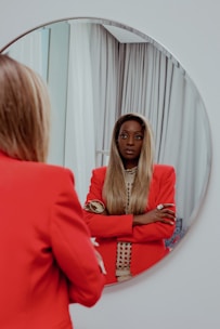 A stylish woman adjusting her custom-designed jacket in front of a mirror.