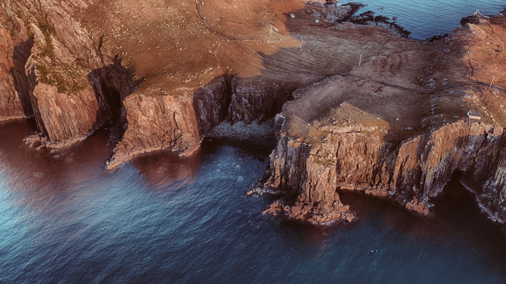 a rocky cliff with a body of water below