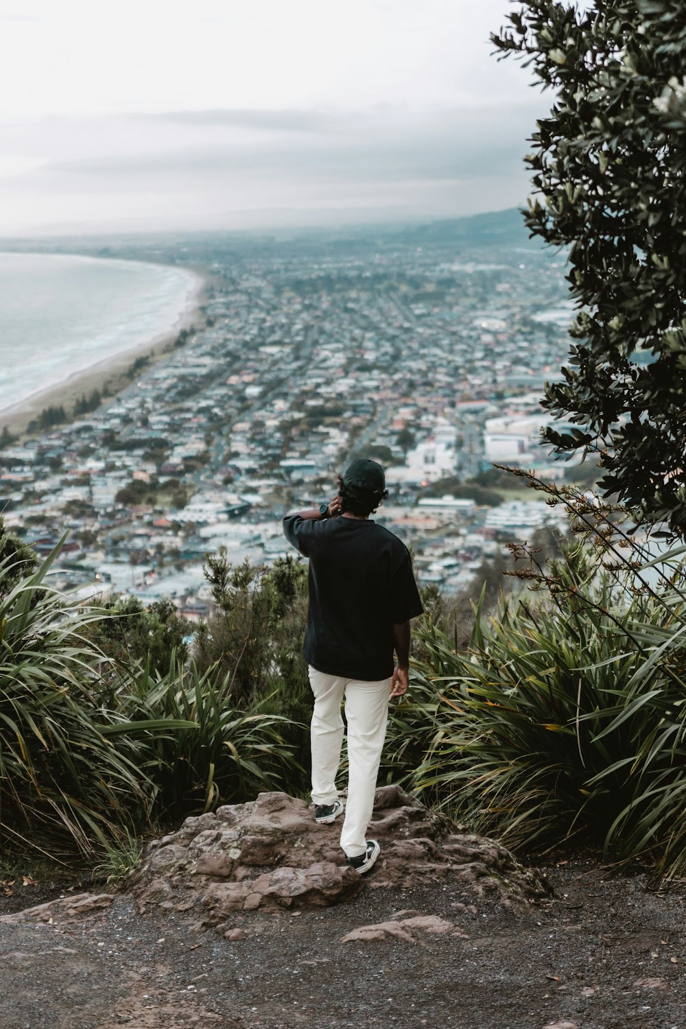 Ein Mann steht auf einer Klippe mit Blick auf eine Stadt