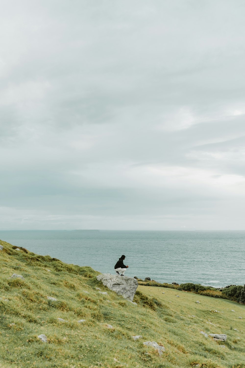 Una persona in piedi su una roccia che si affaccia sull'oceano