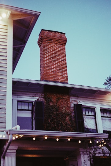 A friendly chimney sweep technician cleaning a brick chimney on a cozy home.