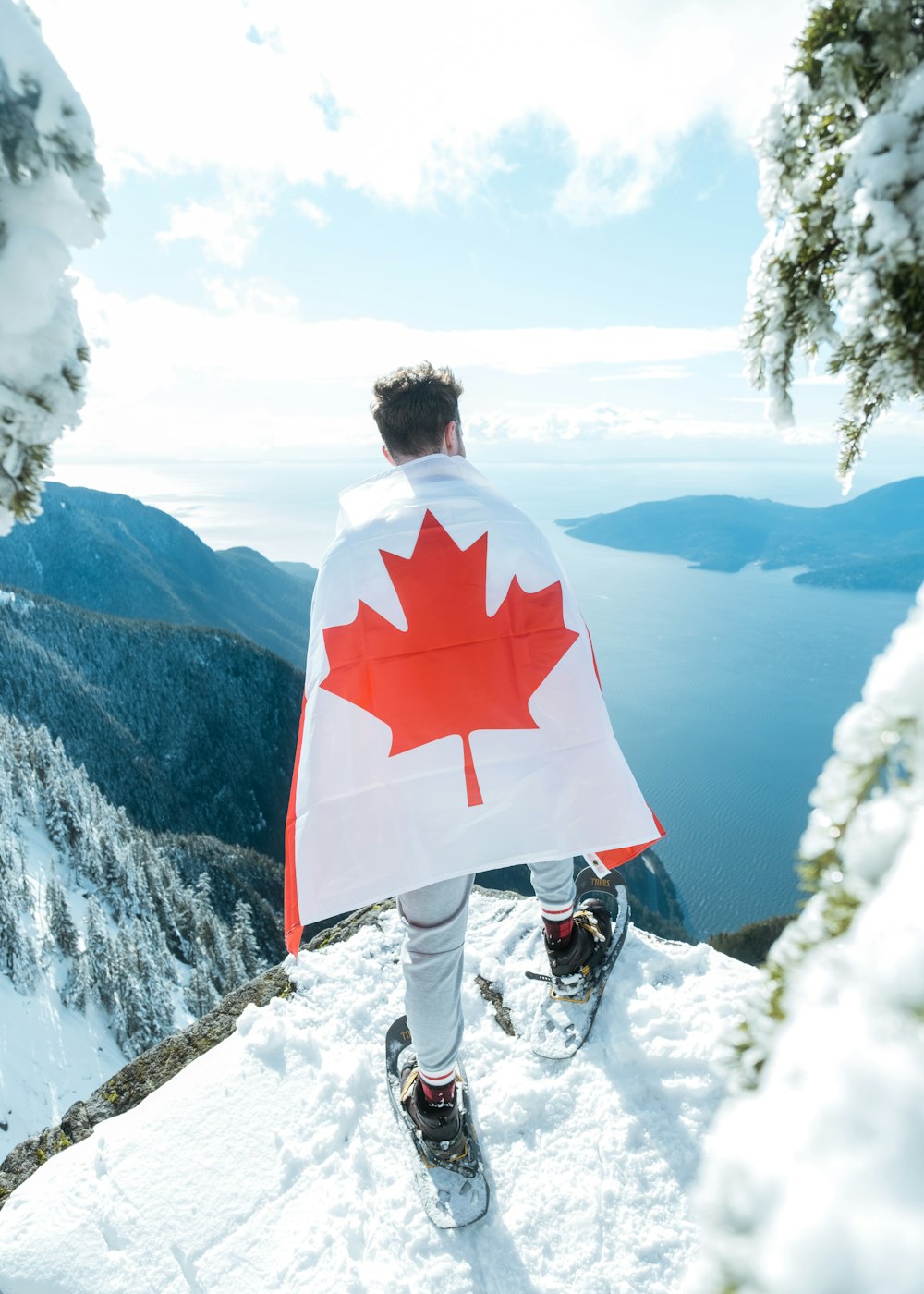 a man wearing a red and white jacket and white pants standing on a snowy mountain