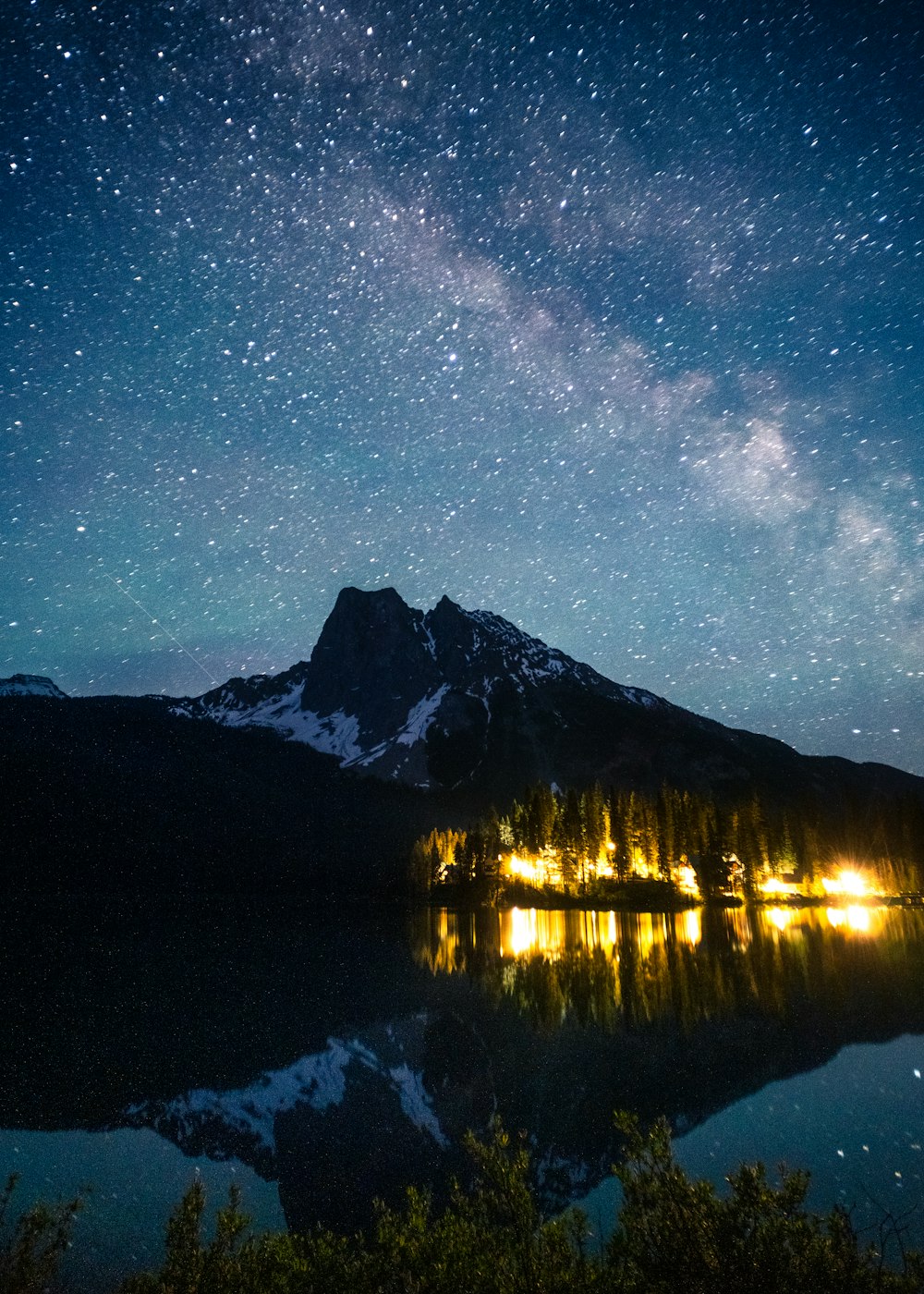 Un lago con una montaña y estrellas en el cielo