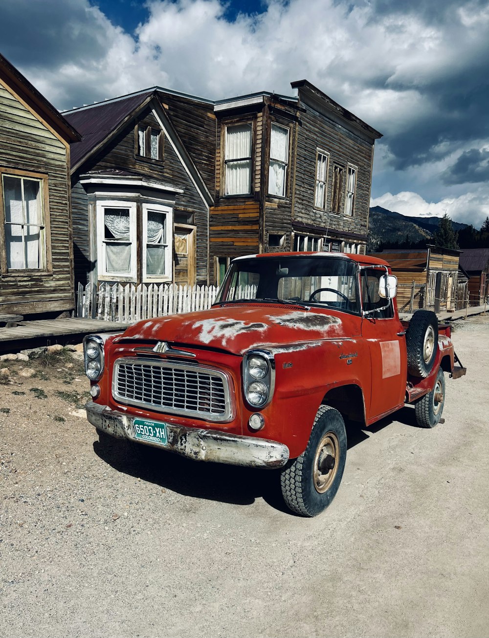 an old red truck parked in front of a house