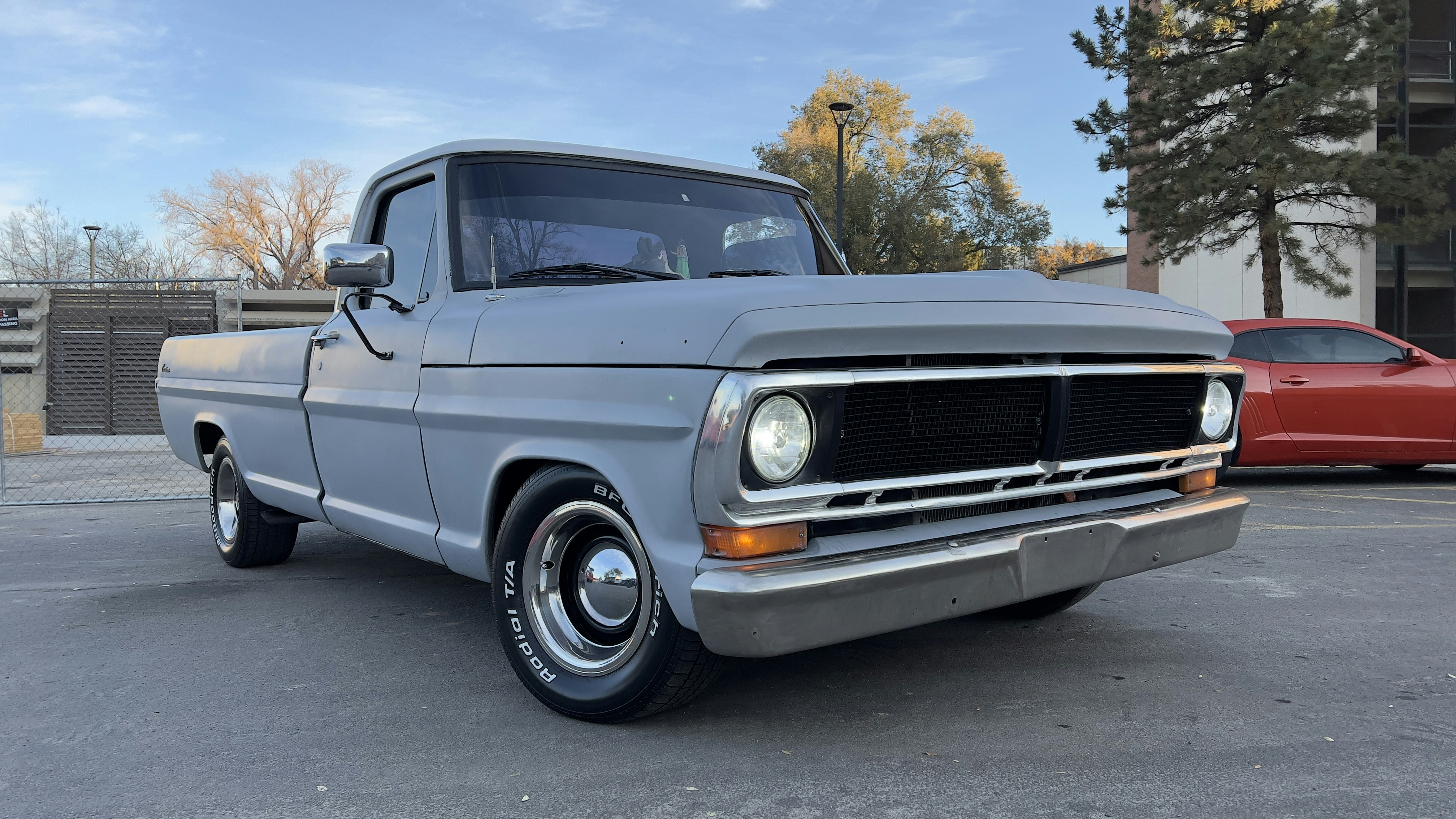Truck with dull oxidized paint before polishing, outdoor parking lot, flat grey finish