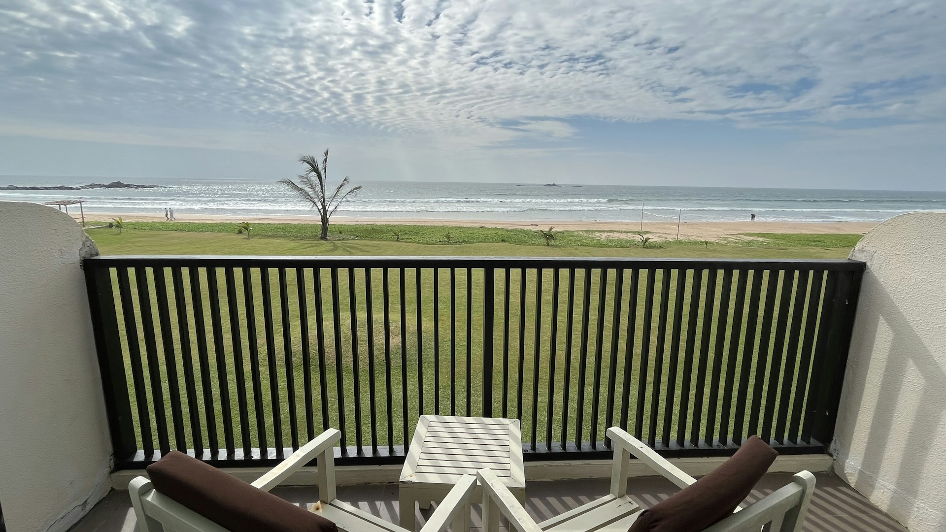 Relaxing balcony overlooking the beach with comfortable seating and soft pastel cushions