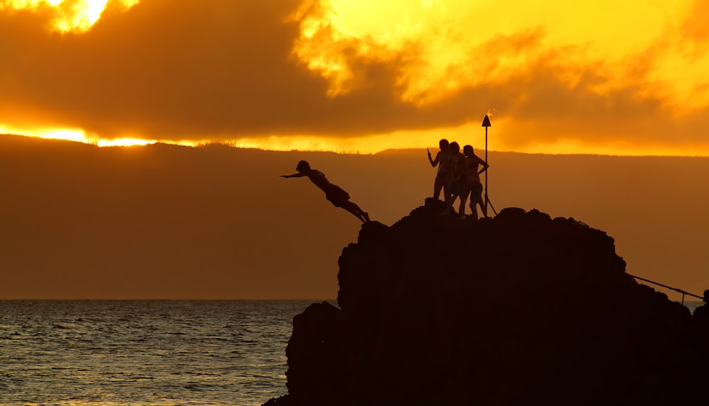a group of people standing on a rock with a sunset in the background