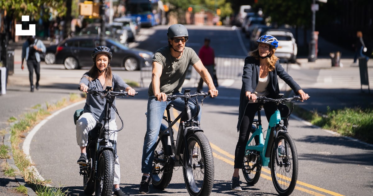 A group of people riding bikes on a street photo – Free Ebike Image on ...