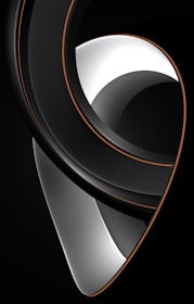 A sleek, abstract design featuring smooth, curved lines with a glossy finish. The composition includes high-contrast sections in black and white, accented with thin, orange borders. The shapes create an enigmatic and modern visual impression.