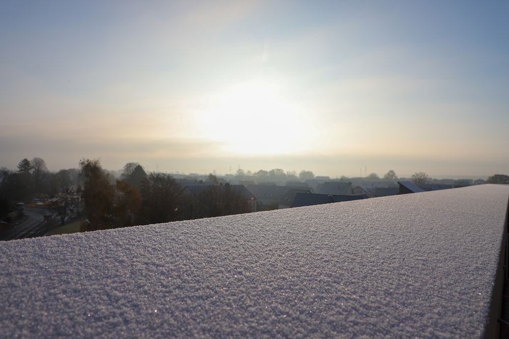 a snowy field with trees and a sun in the background