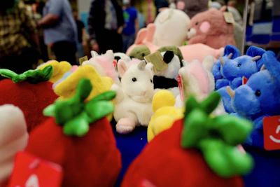 Close-up of soft plush animals and dolls with smiling children playing in the background.