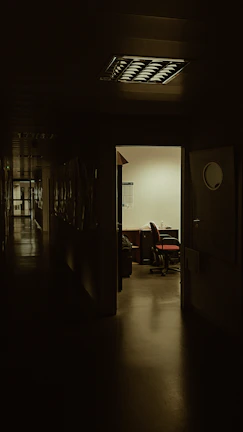 A dimly lit office hallway with a security camera in the corner, highlighting potential blind spots.