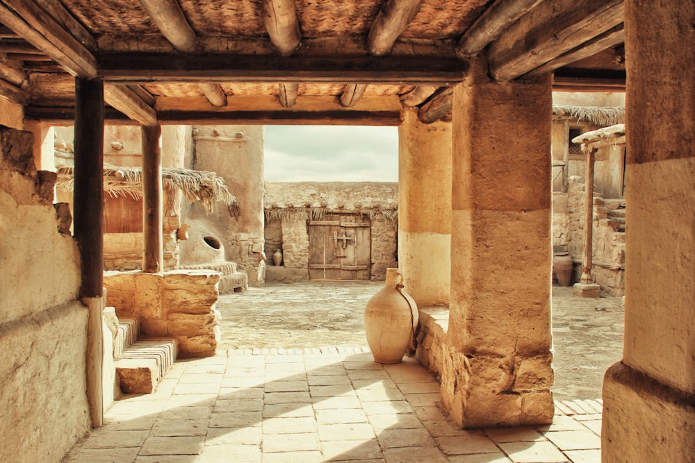 a room with a stone floor and a vase on the floor