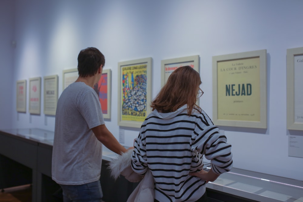 a man and a woman looking at a wall of posters