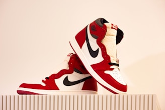 A collection of stylish red and black sneakers displayed on a concrete surface.