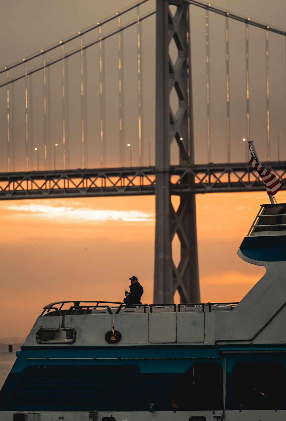 eine Person, die auf einem Boot vor einer großen Brücke sitzt