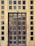 A rustic wooden door is framed by a series of small square glass panels, some of which show signs of wear and age. The glass is slightly opaque, reflecting a bit of the outside environment. The door is adorned with metal rings used as handles.